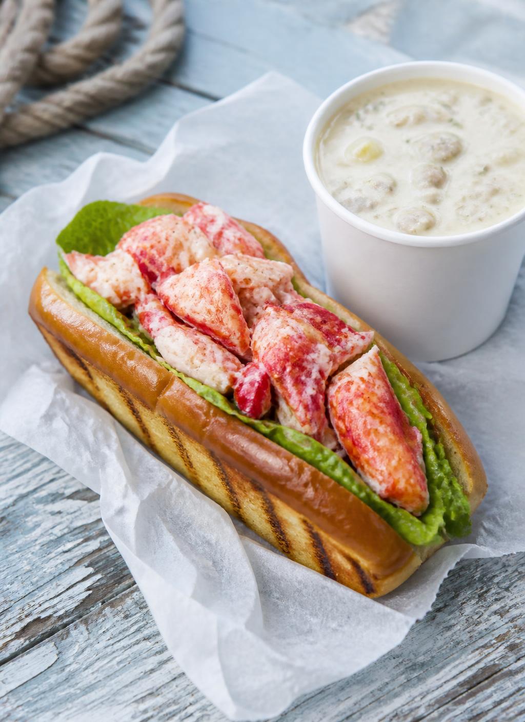 Maine lobster roll on a grilled split-top roll beside a cup of clam chowder